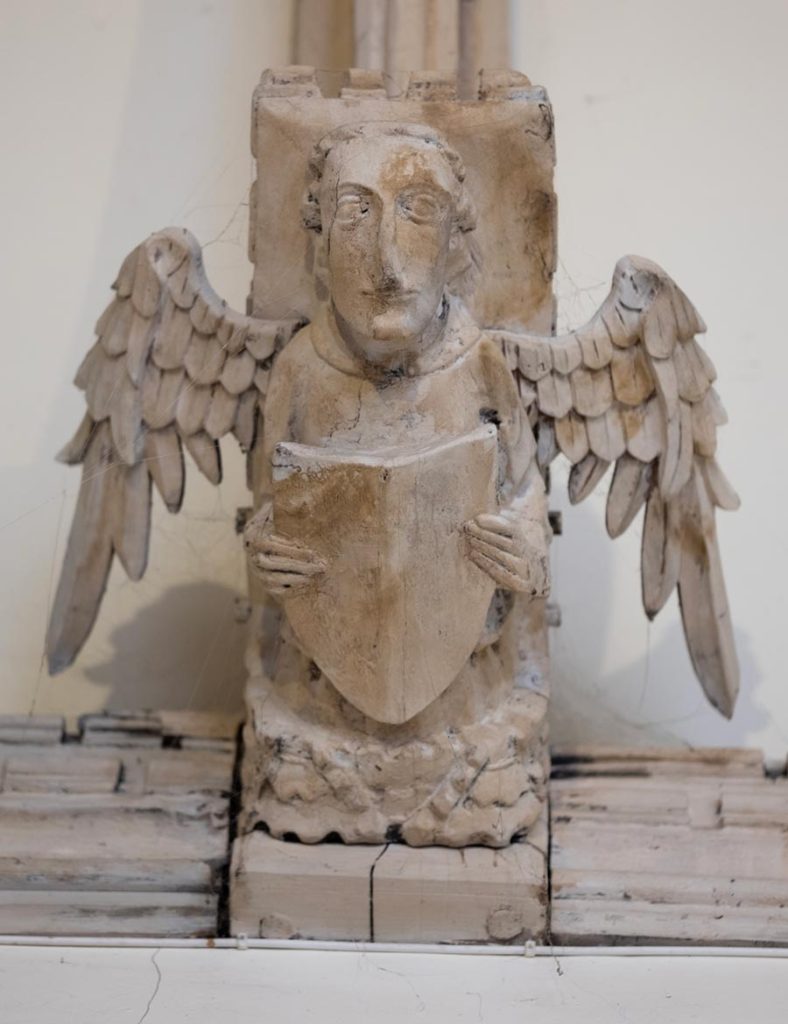 Angel holding shield? / open book?